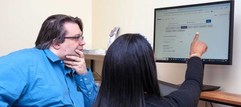 Photo of a staff member pointing something out to a client who is pondering the information.