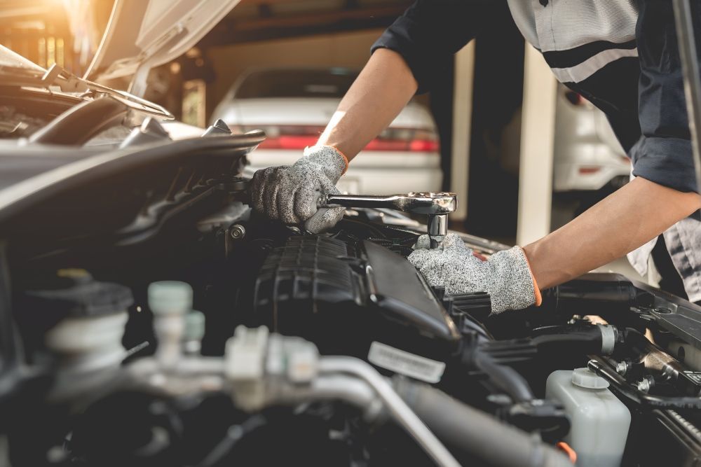 A Mechanic Is Working On The Engine Of A Car In A Garage — Tuned Suspension & Mechanical in Parkes, NSW