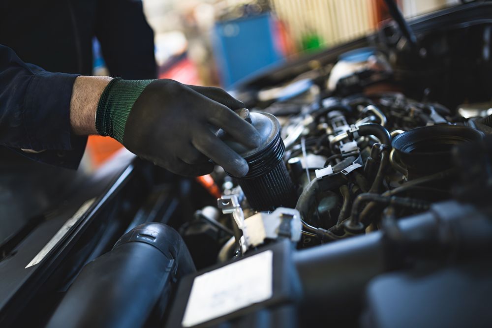 A Man Is Working On A Car Engine In A Garage — Tuned Suspension & Mechanical in Parkes, NSW