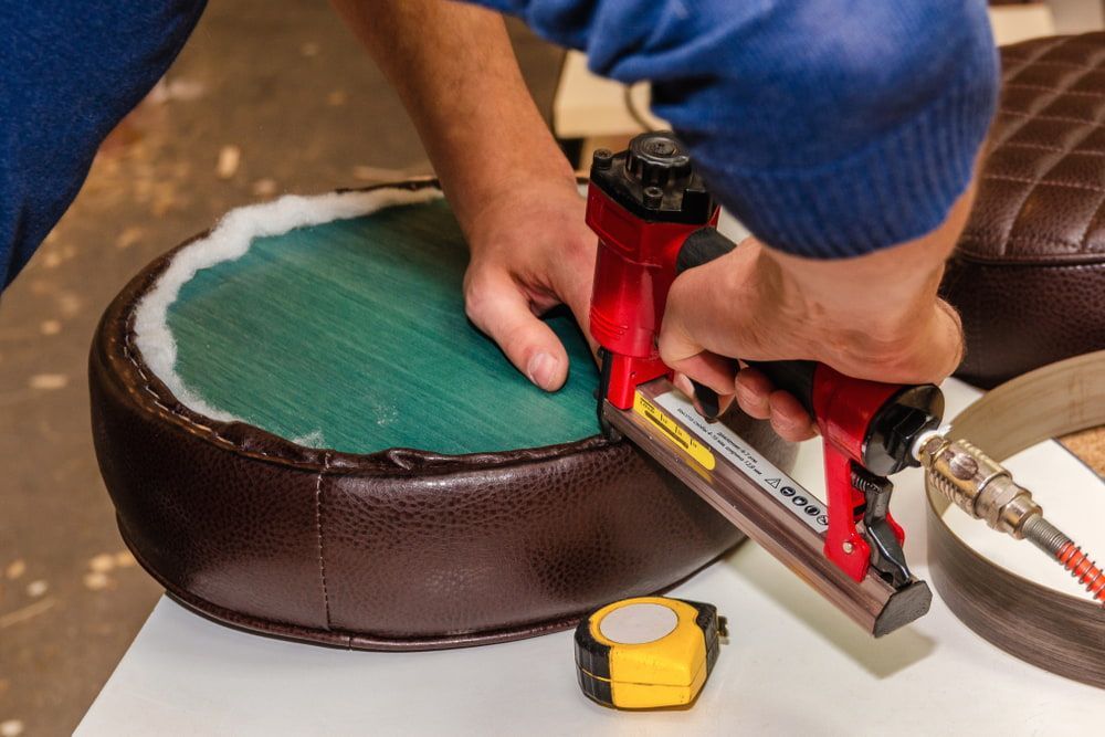 A Person Is Using A Stapler On A Chair Seat — Allwood Upholstery In Manunda, QLD