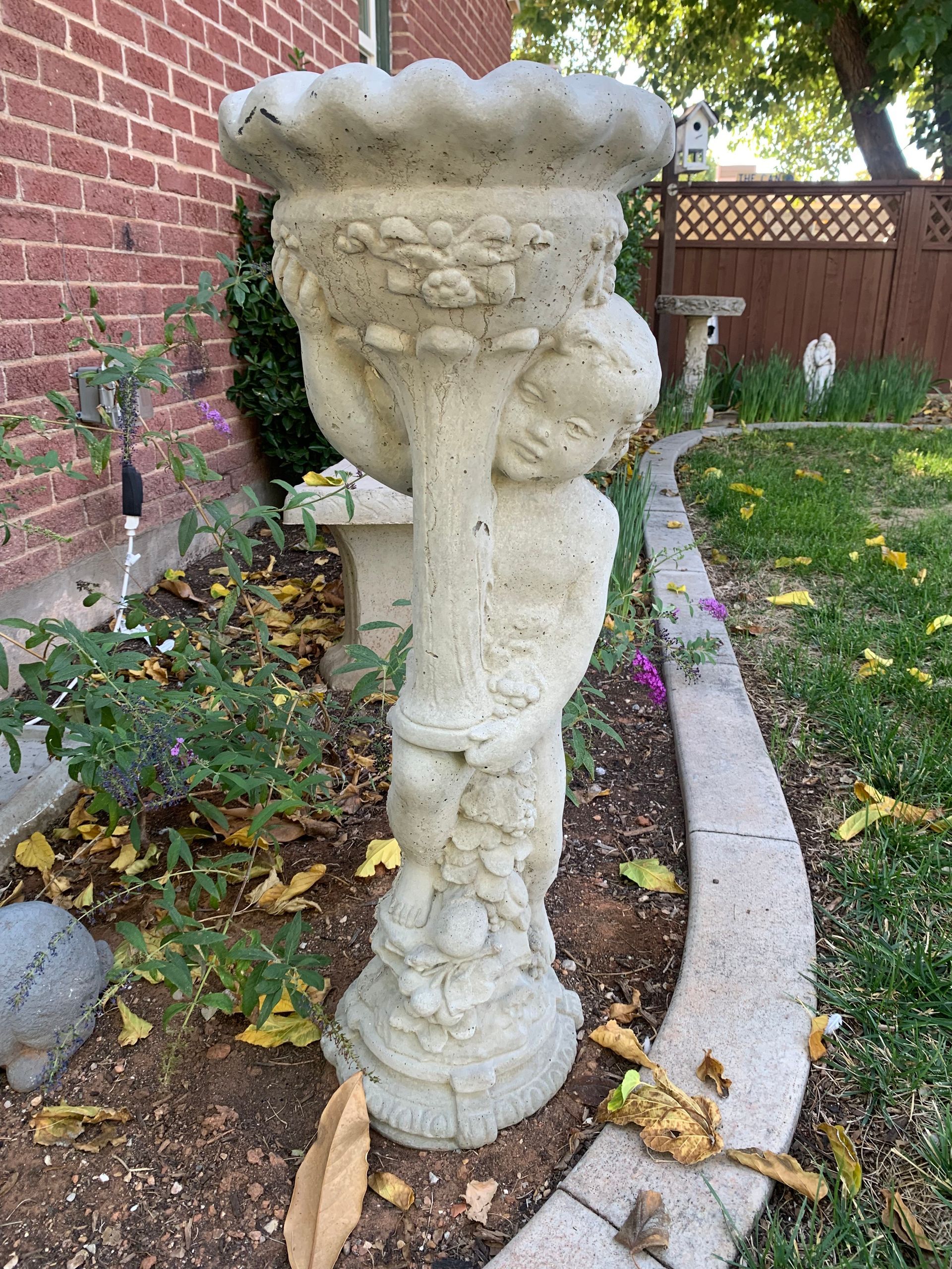 A blue jay is perched on top of a bird bath.