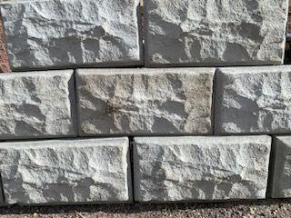 A brick wall with a metal fence behind it.