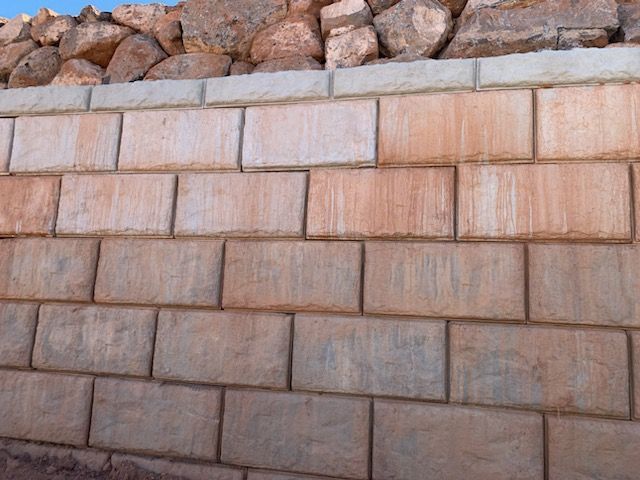 A brick wall with a metal fence behind it.
