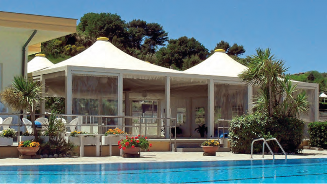Una piscina con una tenda bianca sullo sfondo