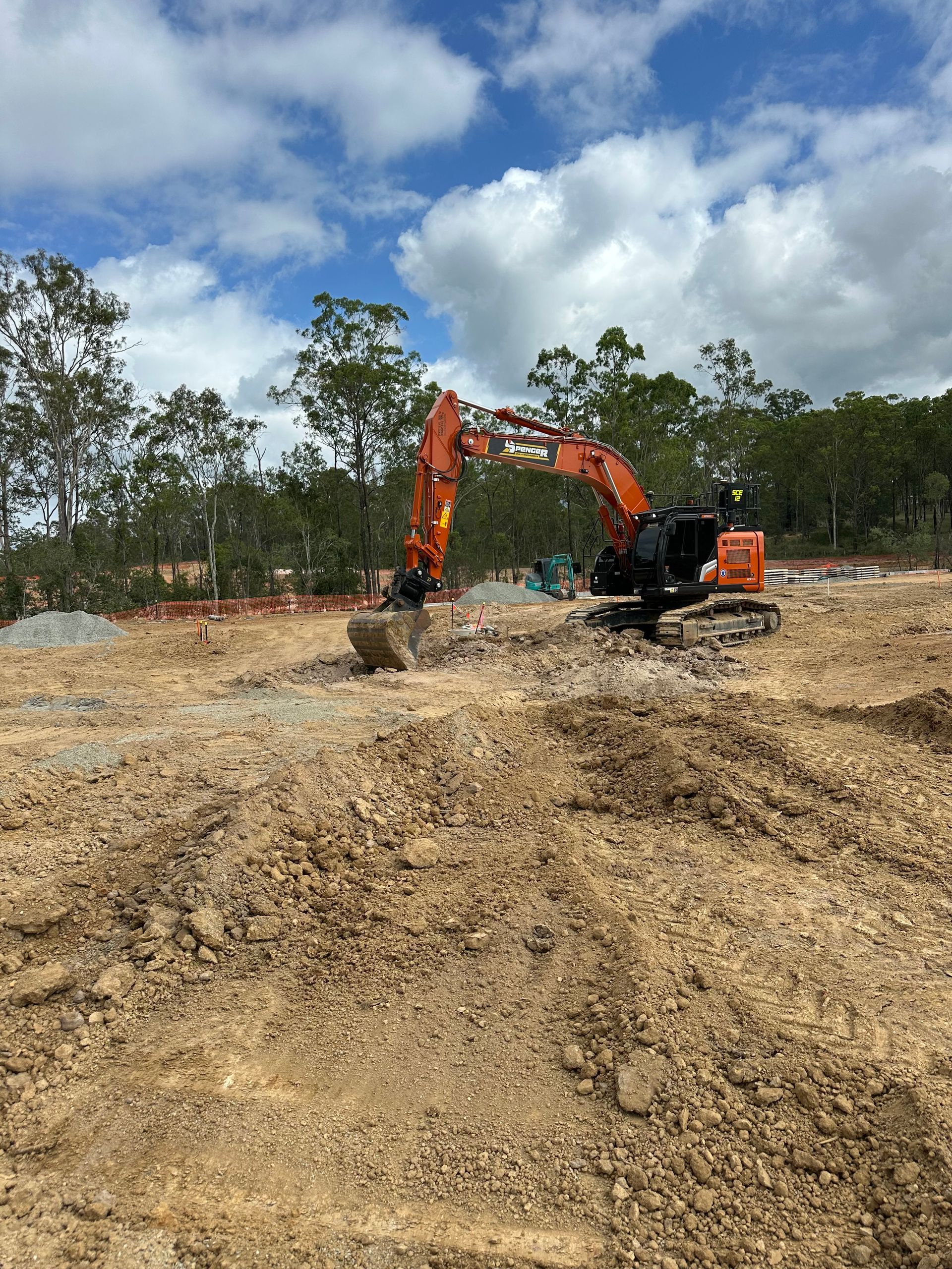 A large levelled dirt pad with a fence in the background. Ready for the next phase of construction.