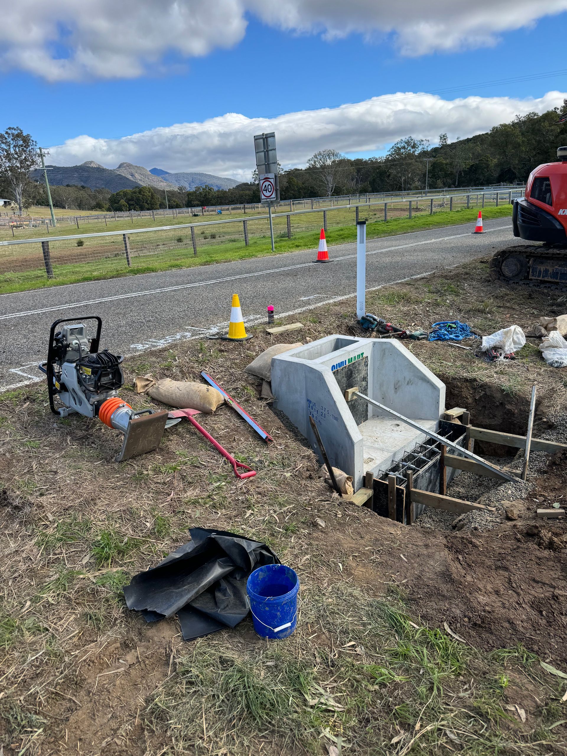 A large concrete drain is being built next to a road.