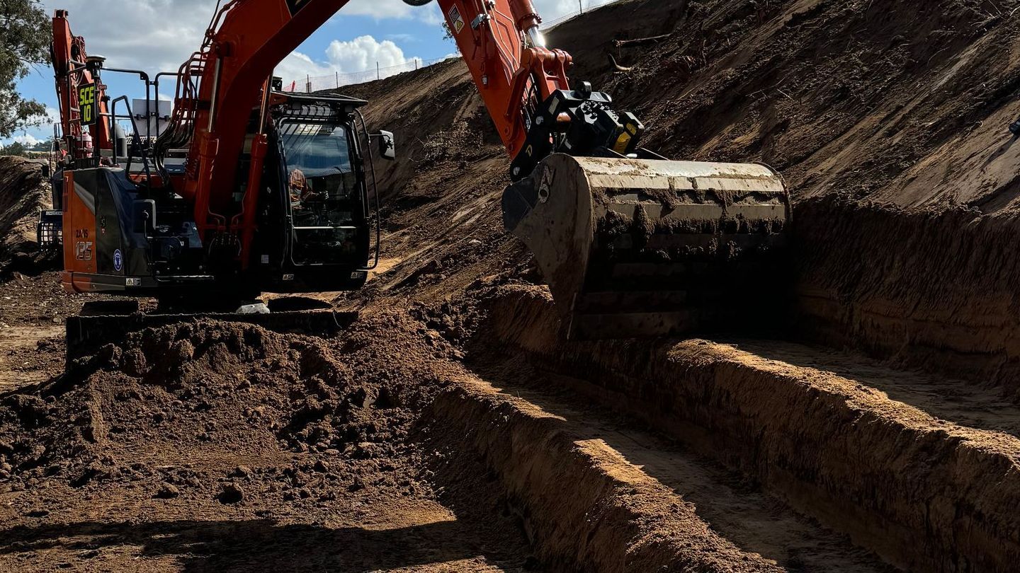 A spencer civil & earthworks excavator is cutting steps into a hillside.