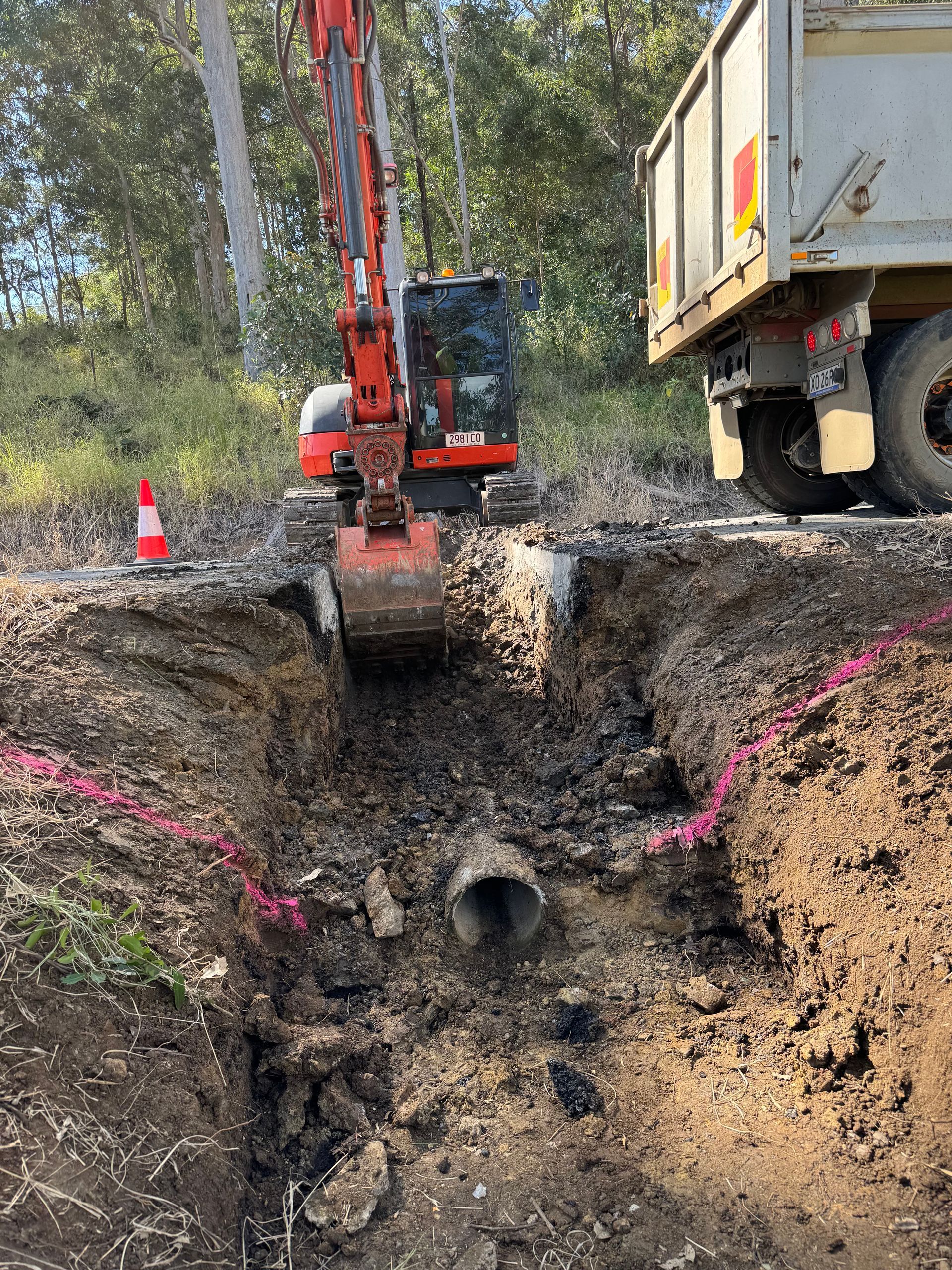 A spencer civil & earthworks excavator is digging a hole in the ground to uncover stormwater pipes.