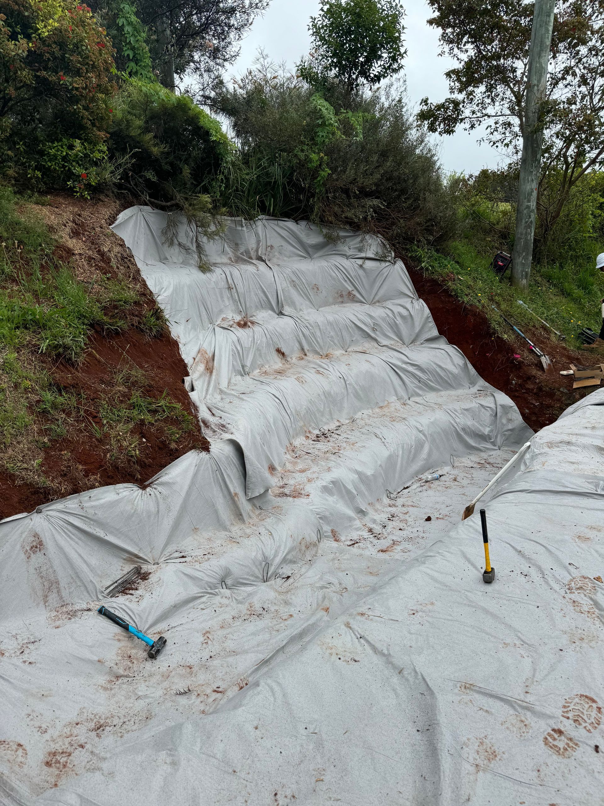 Geotextile matting has been installed along steps cut into a hill.