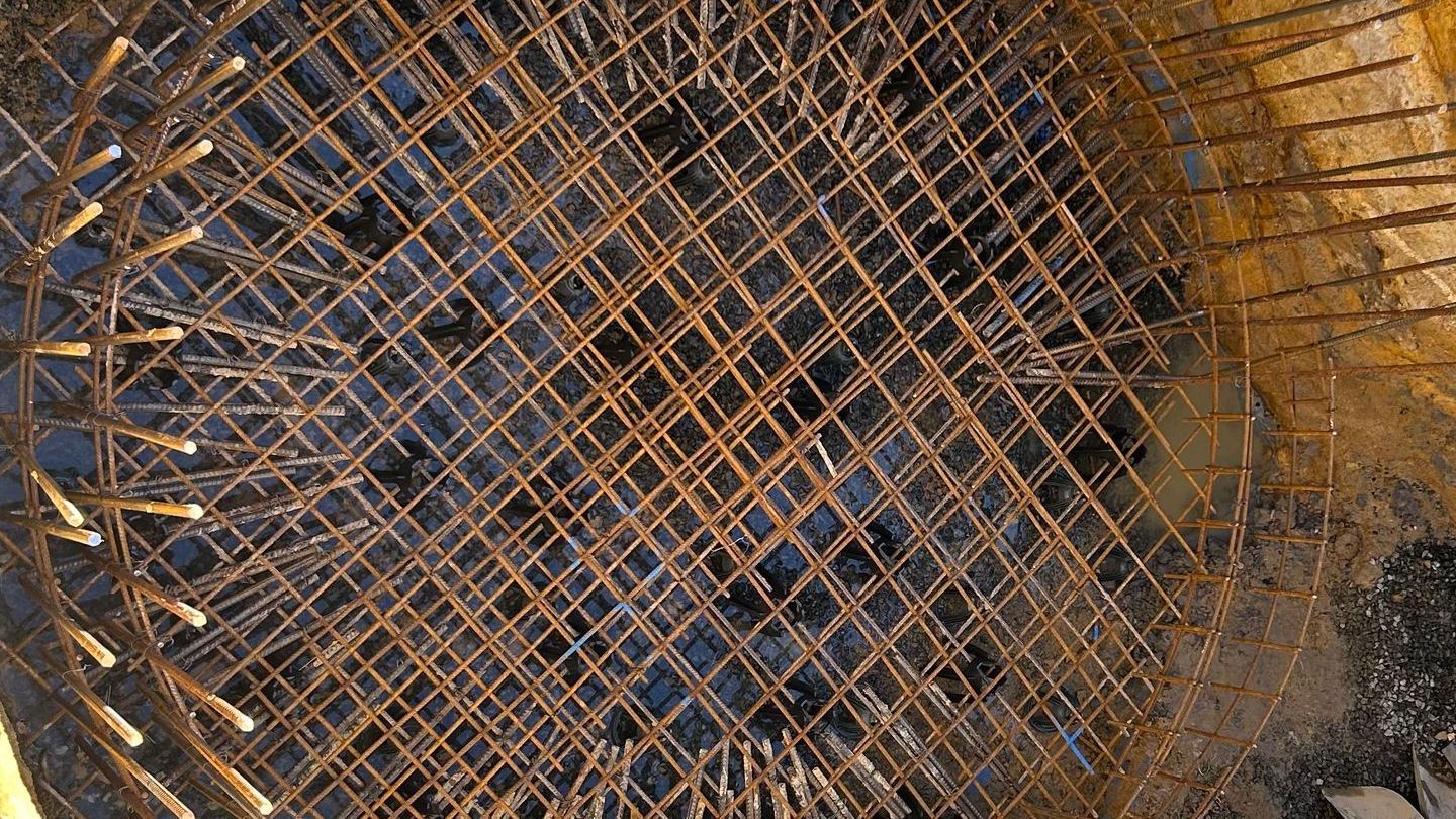 A close-up of a steel metal reinforcement grid in a hole in the ground.
