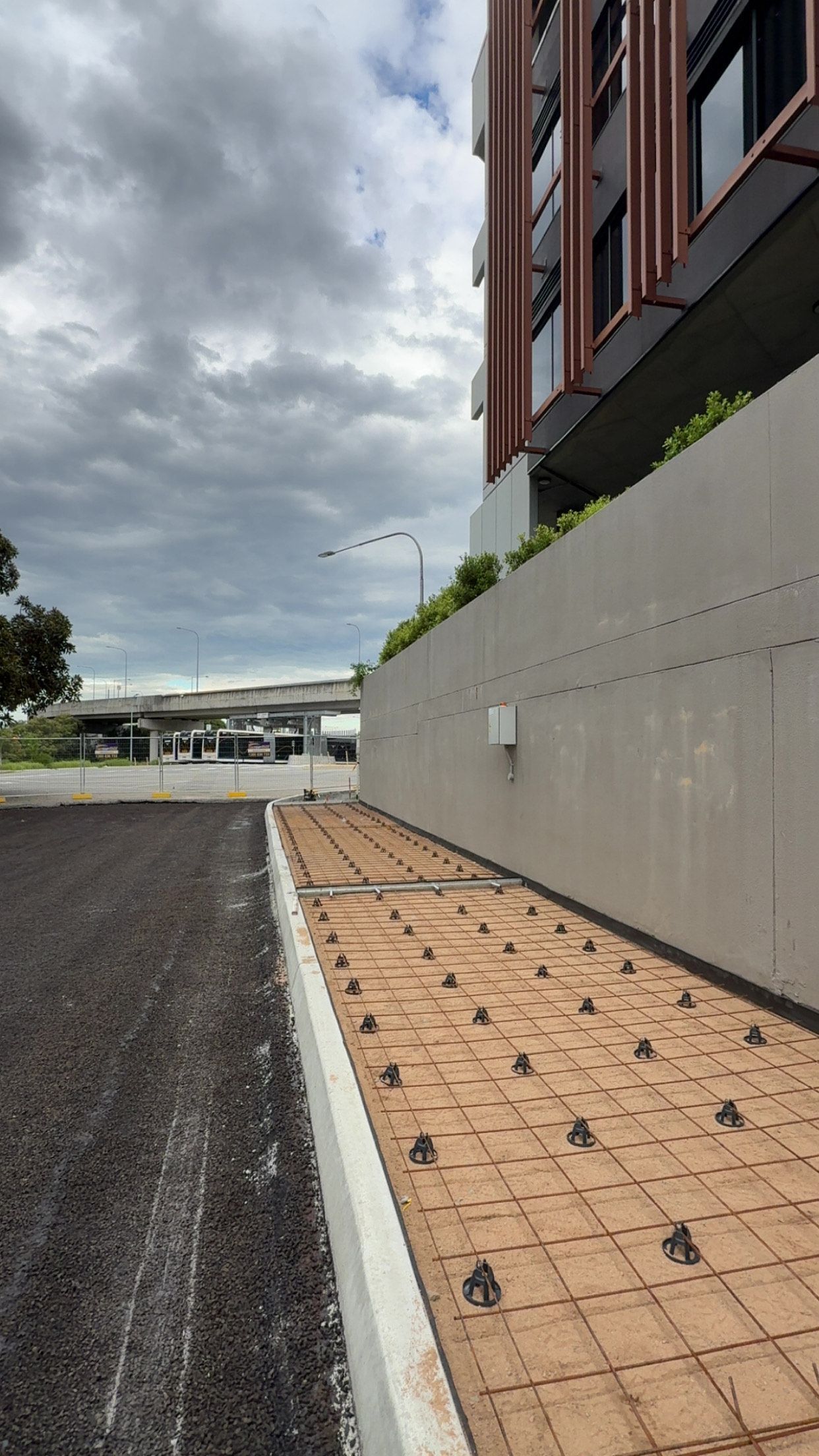 A walkway ready to be filled with concrete eading to a building with a bridge in the background.