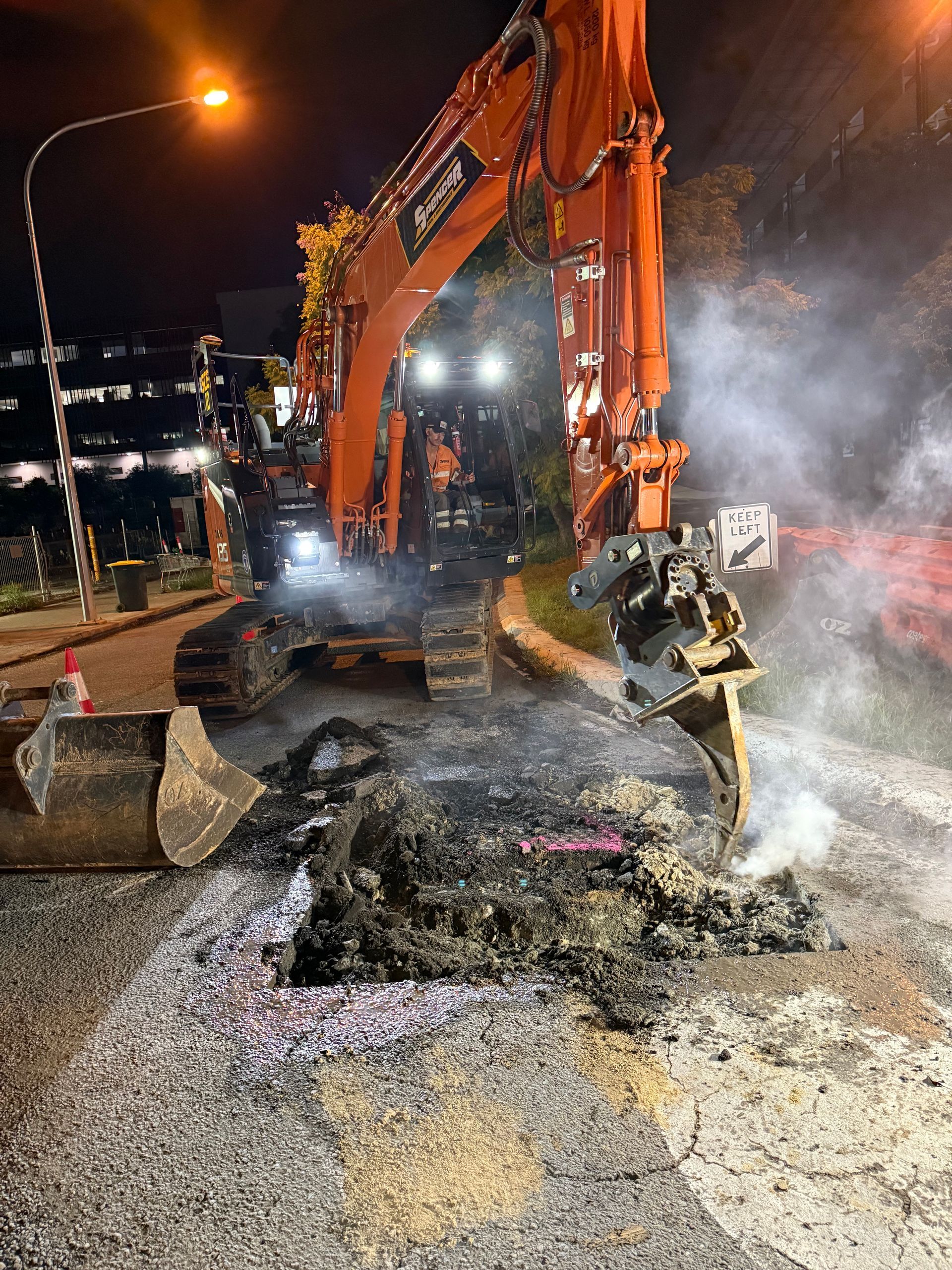 A spencer civil & earthworks excavator using its ripper attachment to break up bitumen.