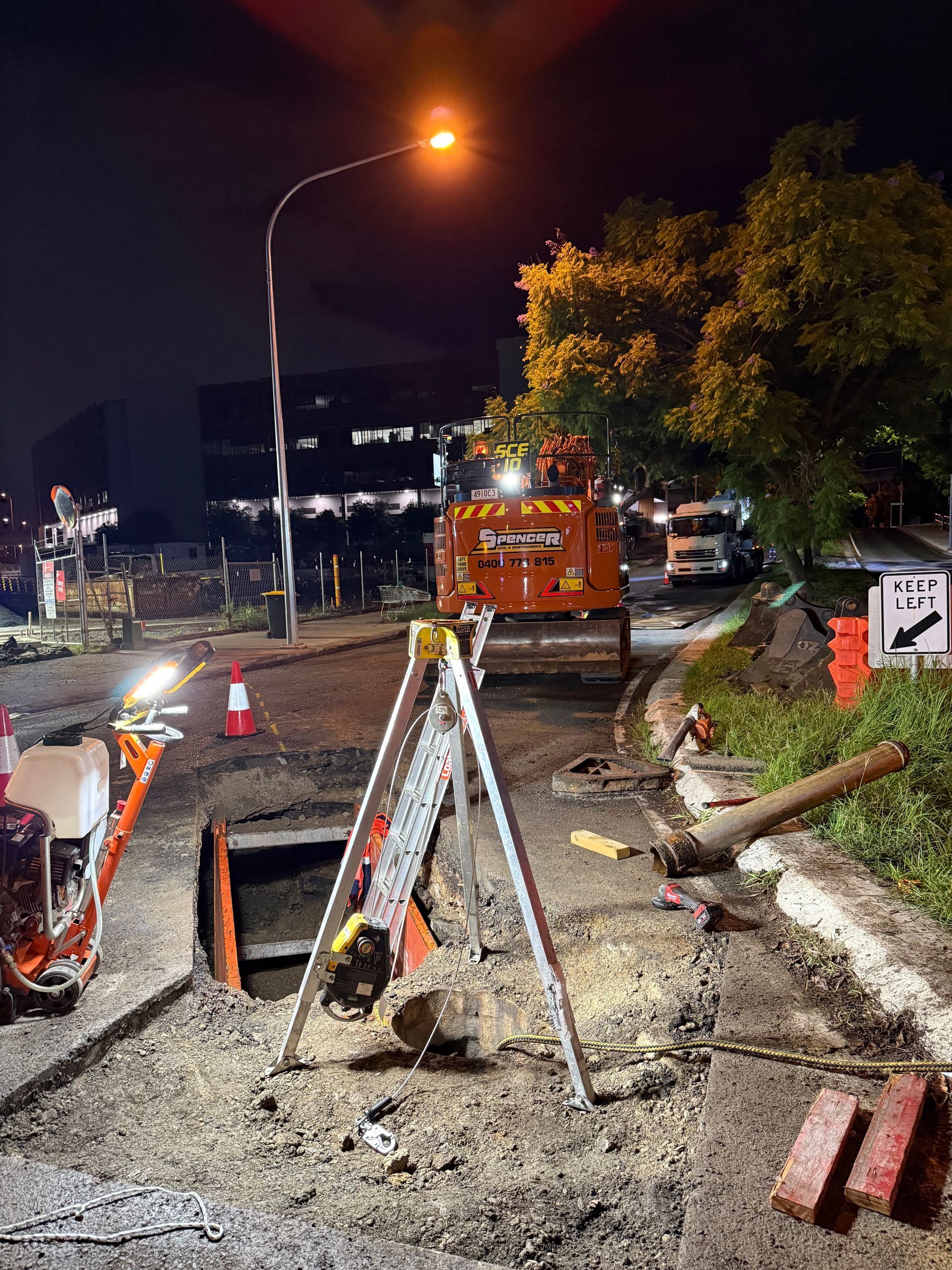 Ongoing progress on a project on butterfield street. there is an open hole in the ground with ladders and equipment.