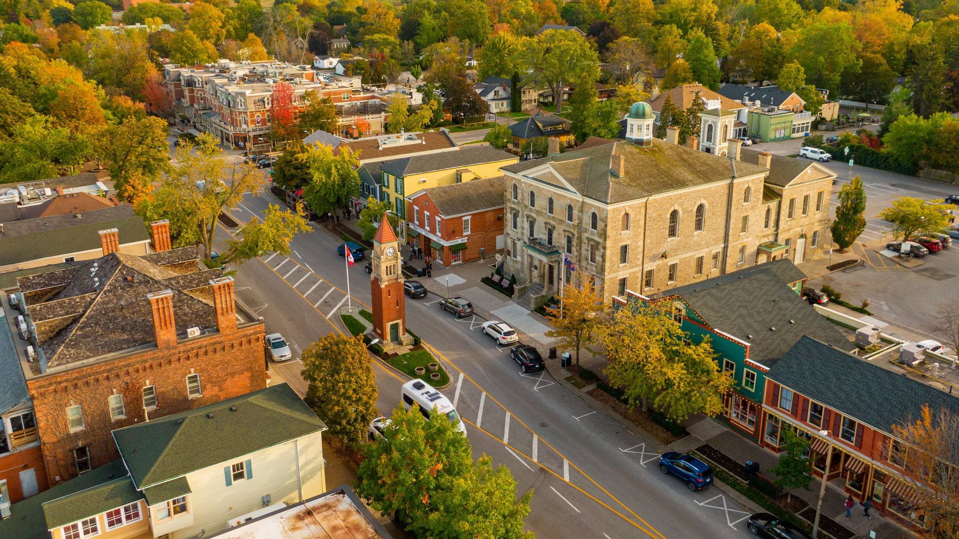 An aerial view of a small town with a clock tower in the middle of the street.
