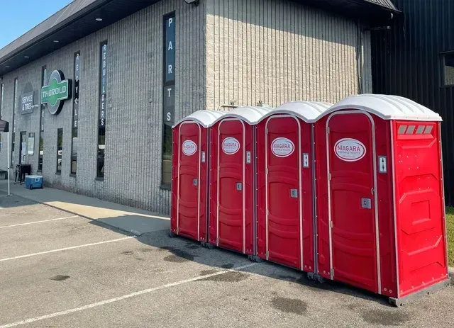 A row of red portable toilets are lined up in front of a building in Niagra Ontario
