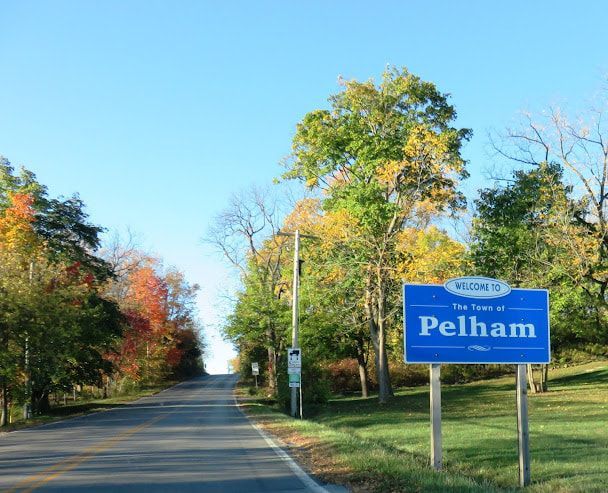 A blue sign on the side of a road that says pelham
