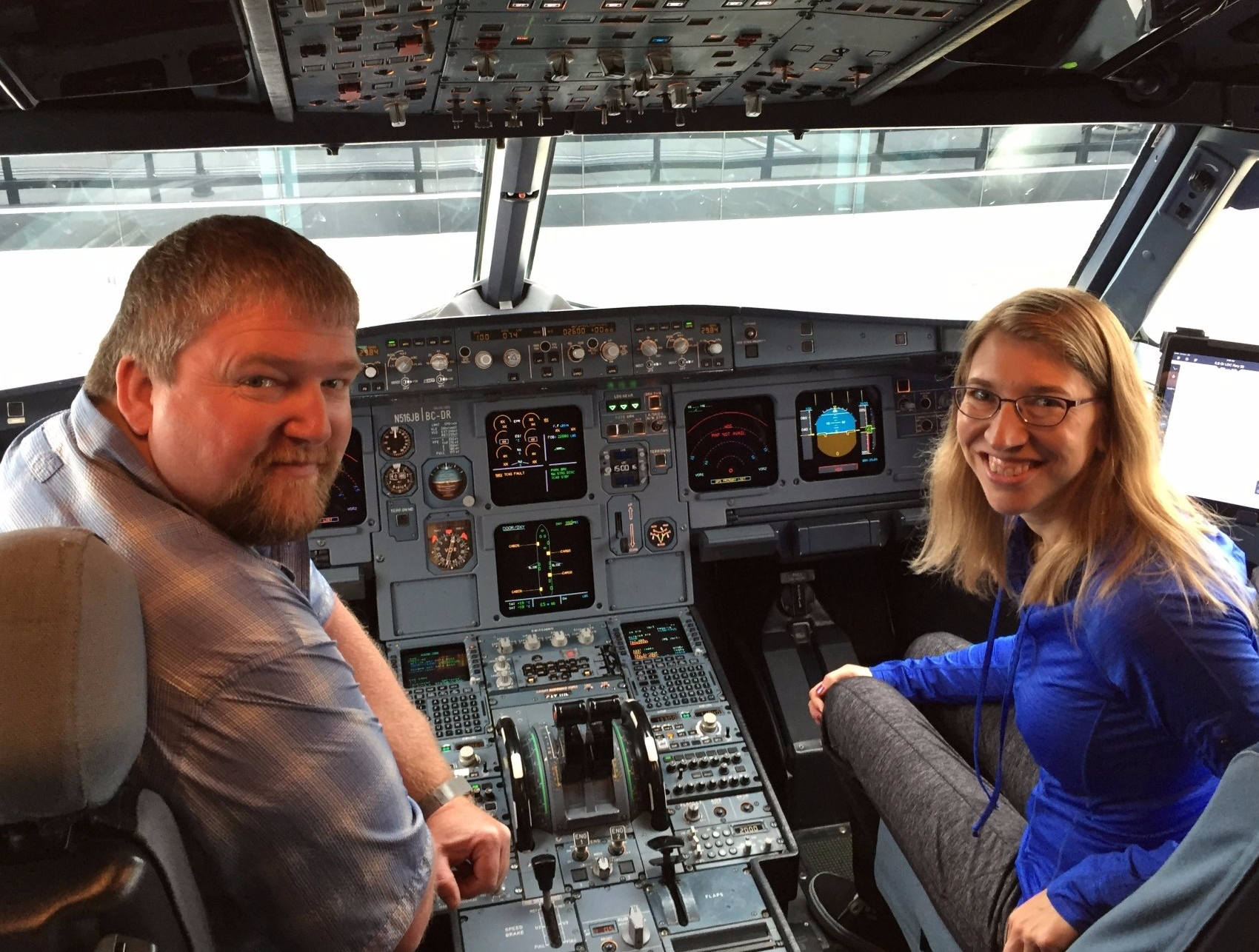 Two people smiling in an airplane cockpit. The man is on the left; the woman is on the right.