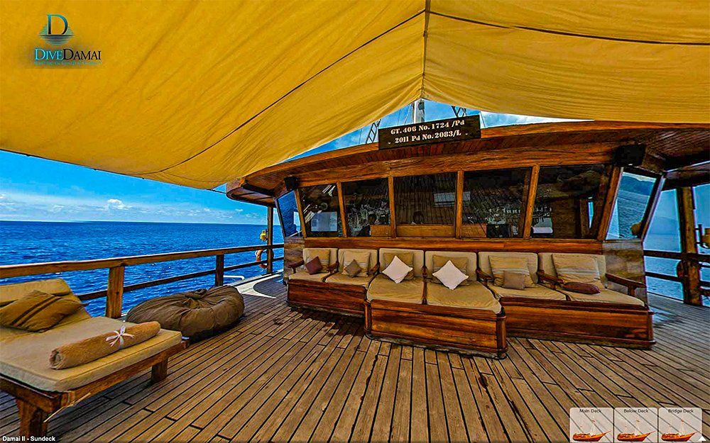 Wooden deck overlooking ocean with lounge seating under a yellow canopy.