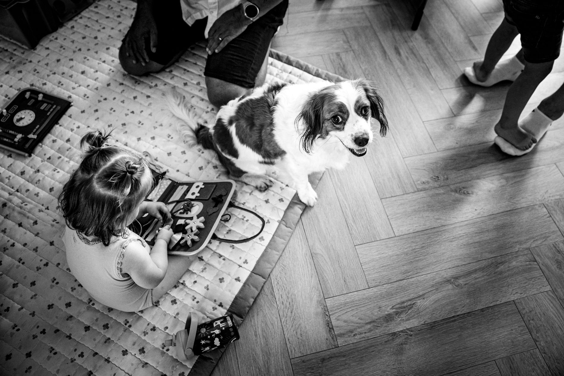 Kind speelt op speelkleed terwijl hond naast haar zit