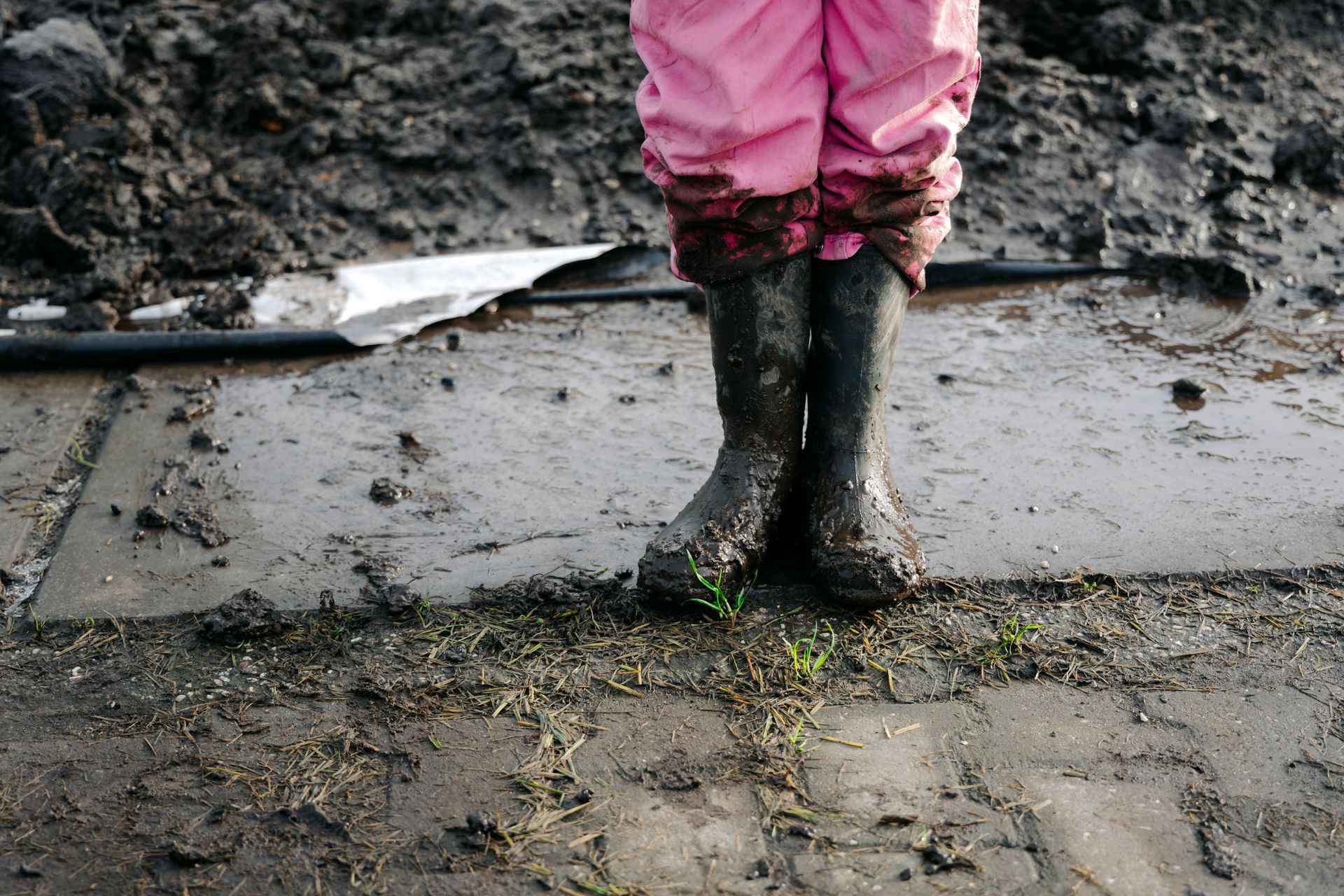 Kinderlaarzen in modder na buitenspelen op het erf