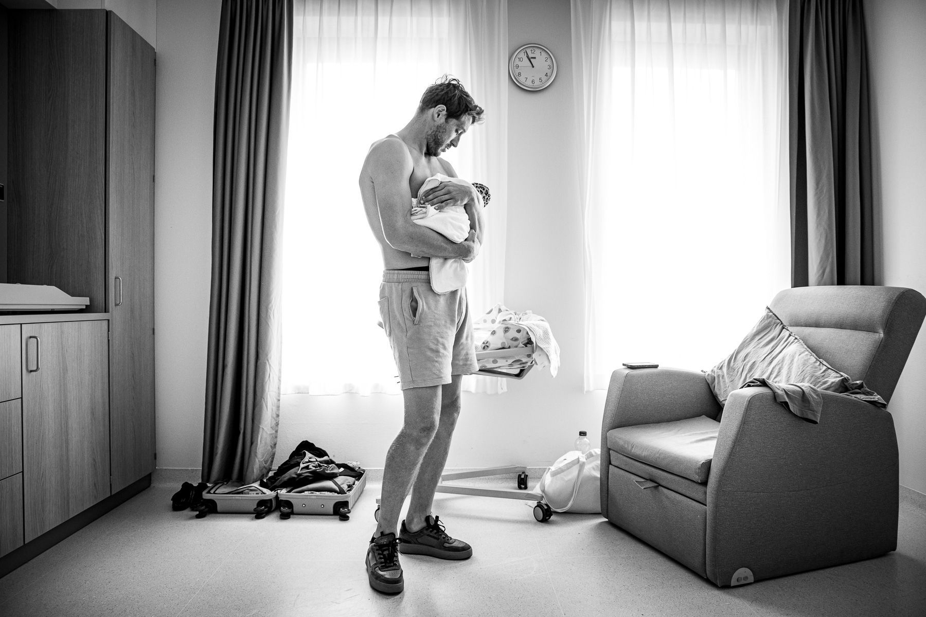Vader houdt zijn pasgeboren baby vast in de ziekenhuiskamer