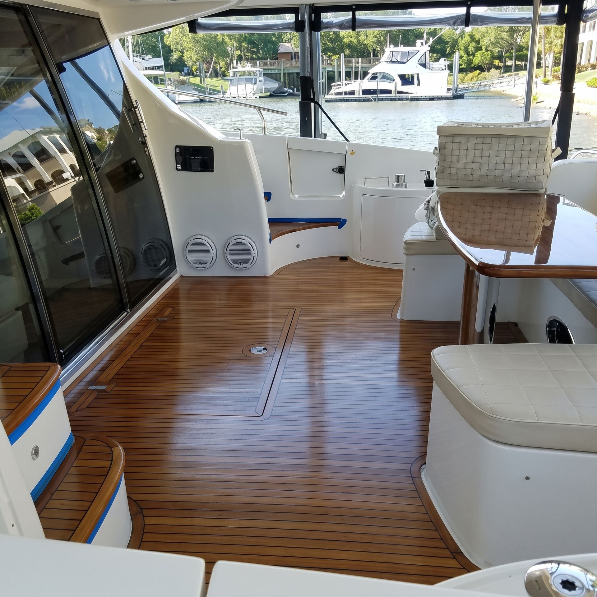 Boat cabin with polished wood floor, white seating, and windows overlooking the marina