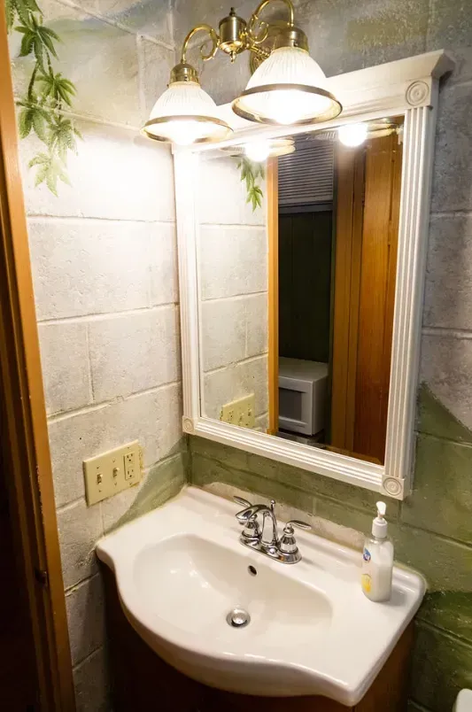 Bathroom with a white sink, mirror, and light fixture. The walls are painted gray.
