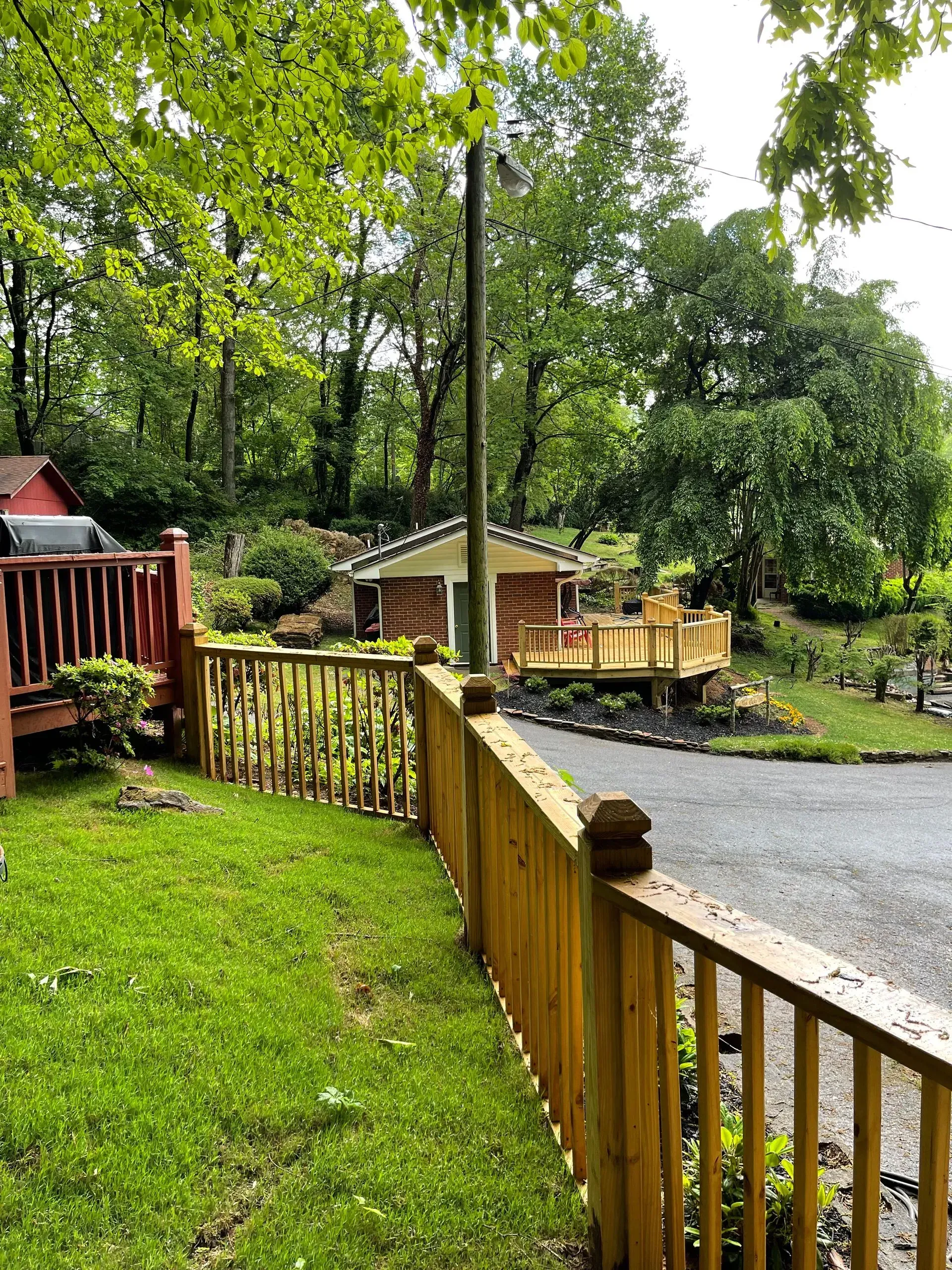 Wooden fence and deck in a green yard, a shed in the background.