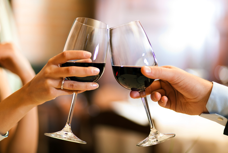 Two people toasting with glasses of red wine.