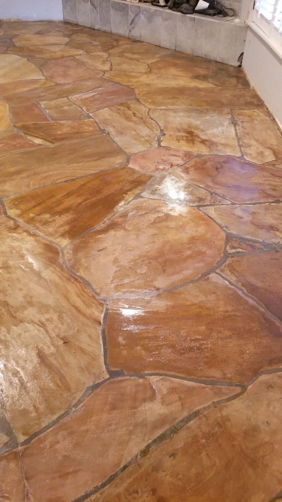 Brown and reddish flagstone flooring with reflective sheen.