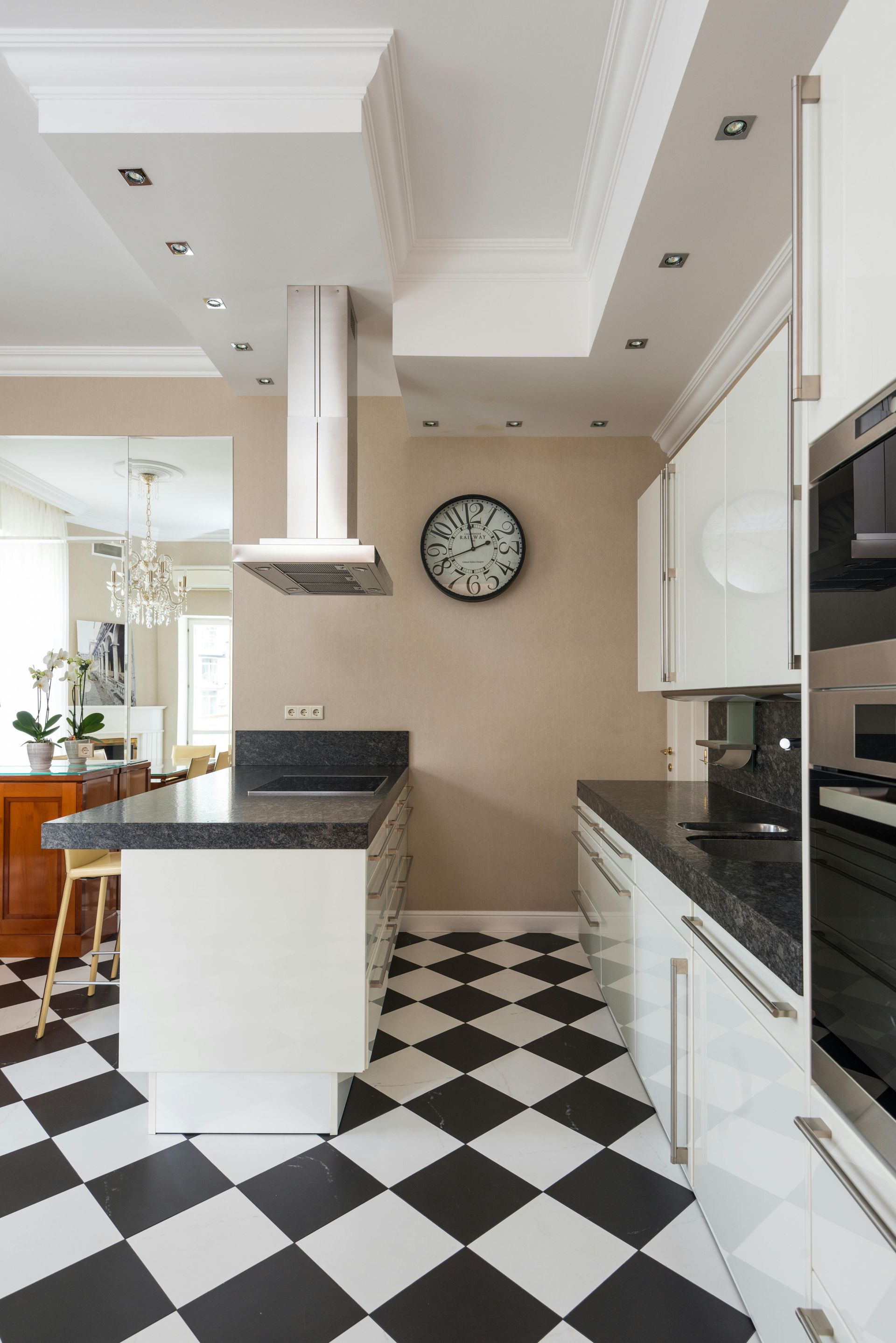 Black and white checkered floor kitchen with white cabinets, island, and stainless steel appliances.