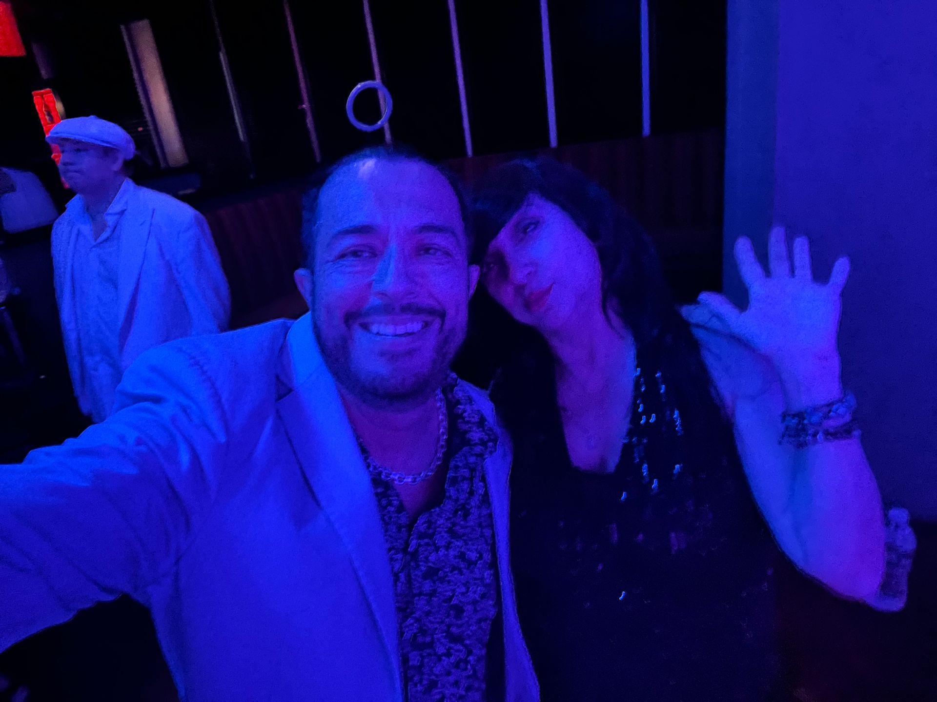 A man and a woman are posing for a selfie in a dark room with blue lights.
