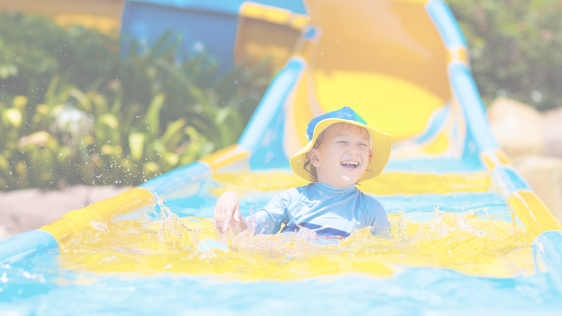 A little boy is playing in a water slide at a water park.