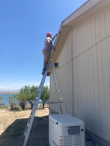 Person on a ladder working on the side of a beige house beside an outdoor HVAC unit.