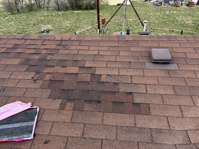 Roof shingles with a pink tarp on the left and a vent on the right, viewed from above.
