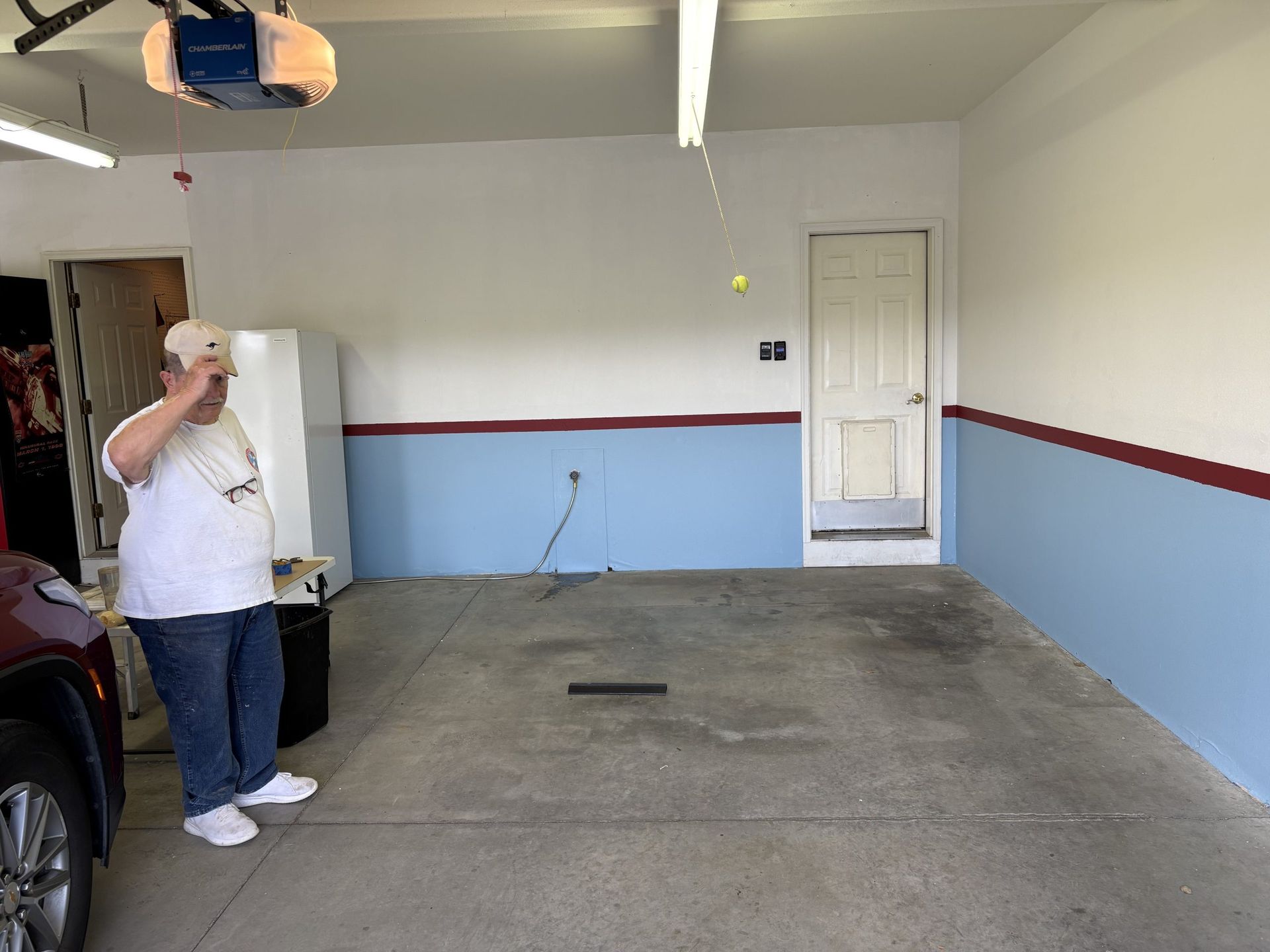 Empty garage with blue-and-white walls, a parked car, and a person standing near the left side.