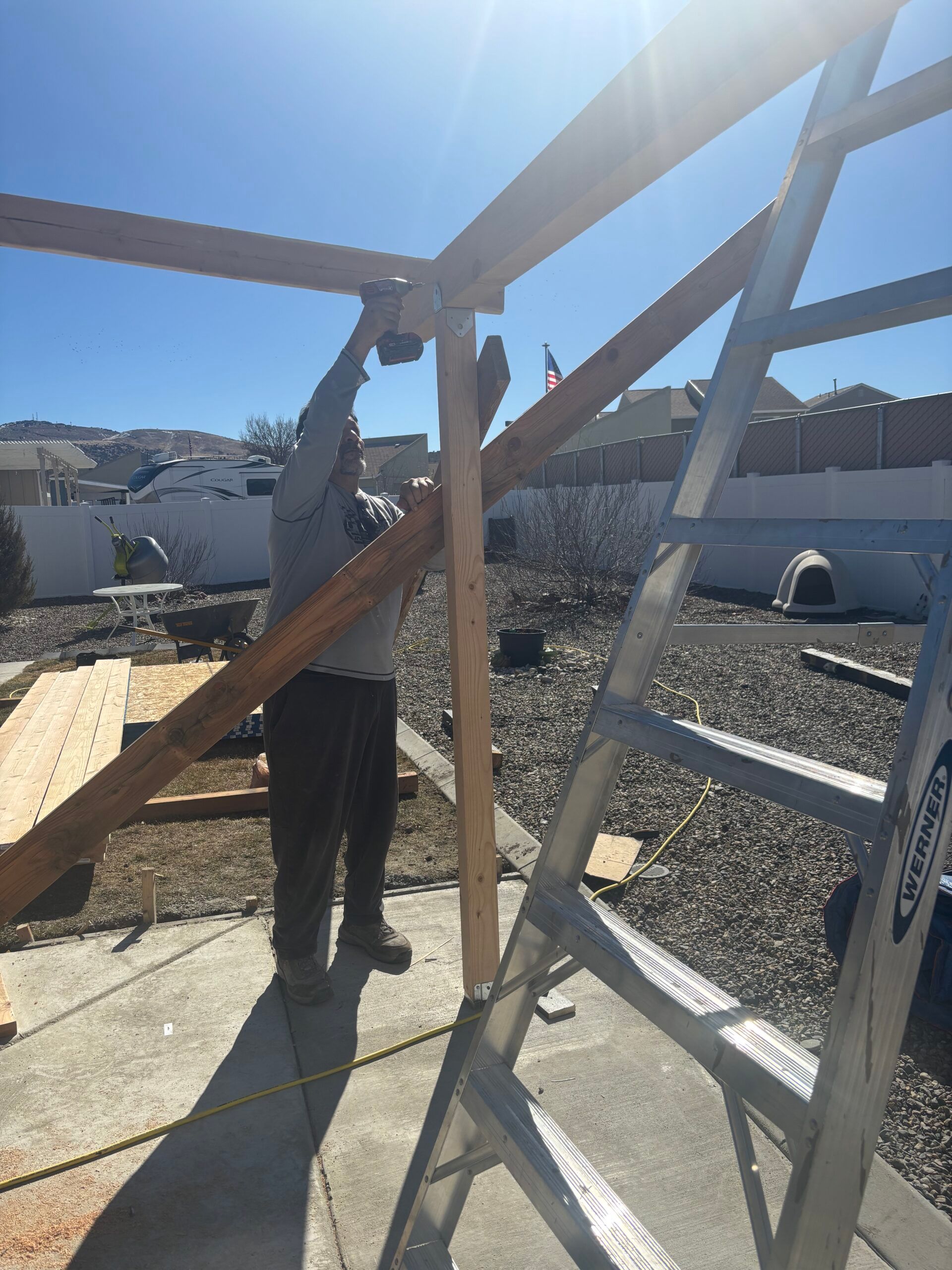 Person standing in sunlight assembling a metal frame on a rooftop