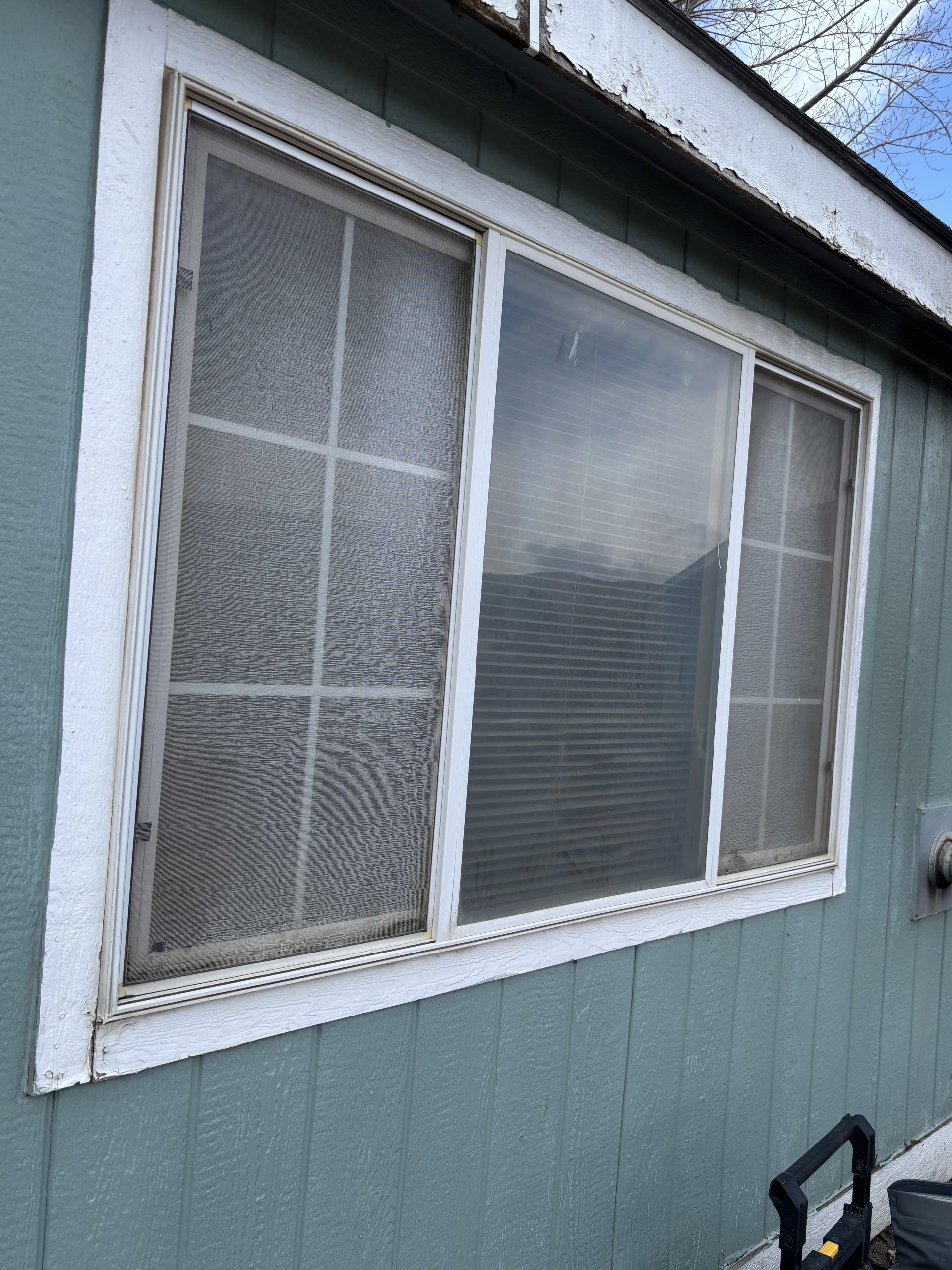 Exterior window with frosted glass and white trim on a blue-gray house wall