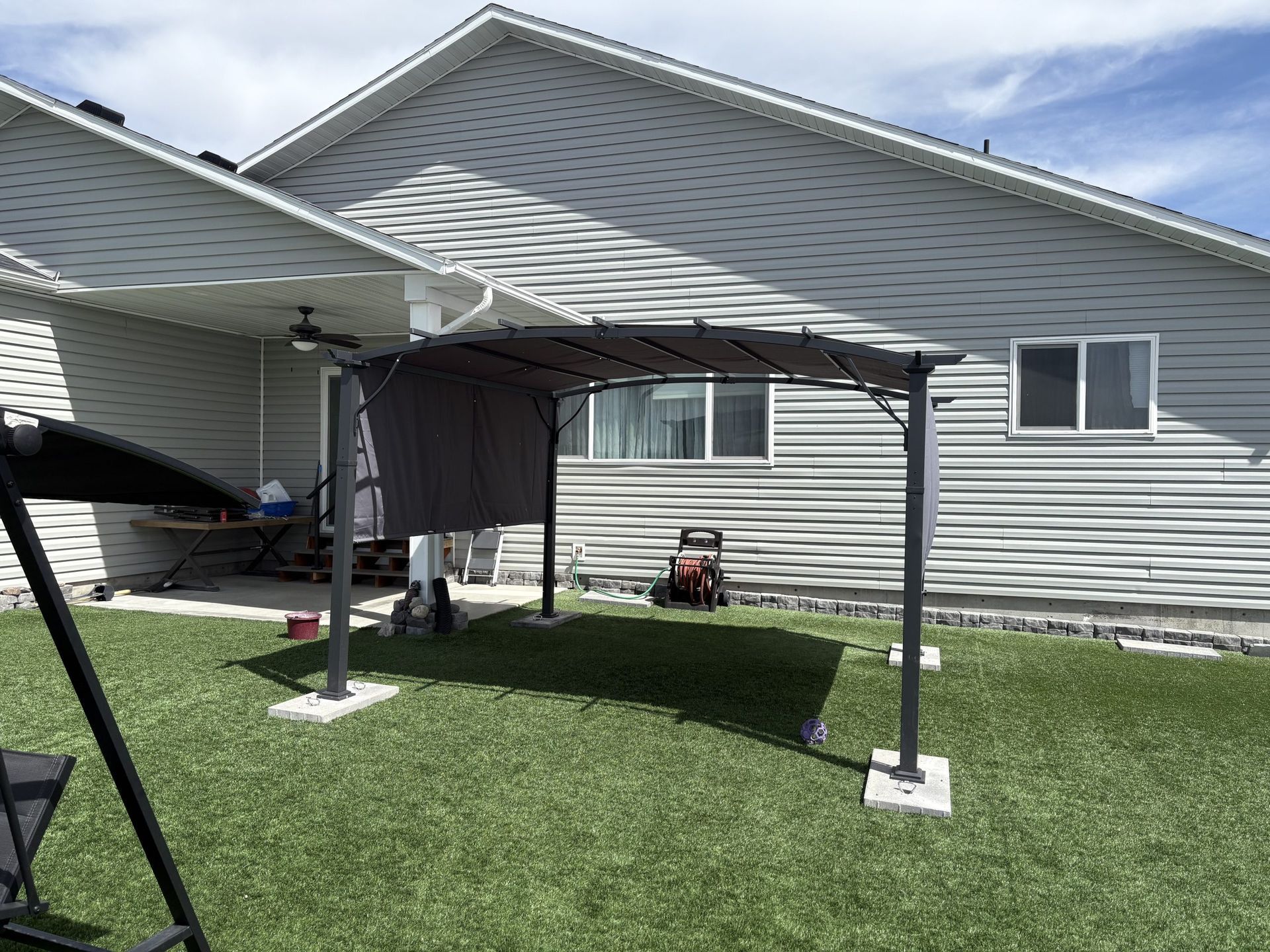 Canopy tent beside a gray house on a sunny lawn