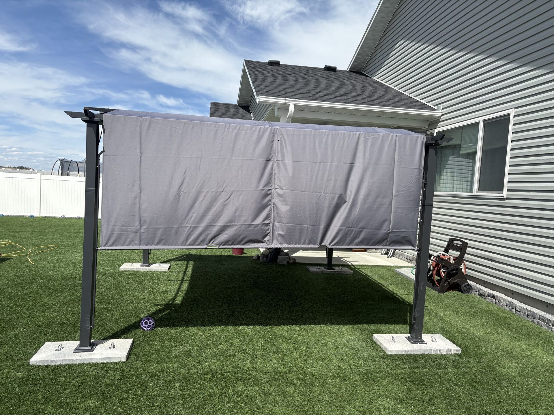 Gray canopy tent on grass beside a house, with a red lawn mower underneath.