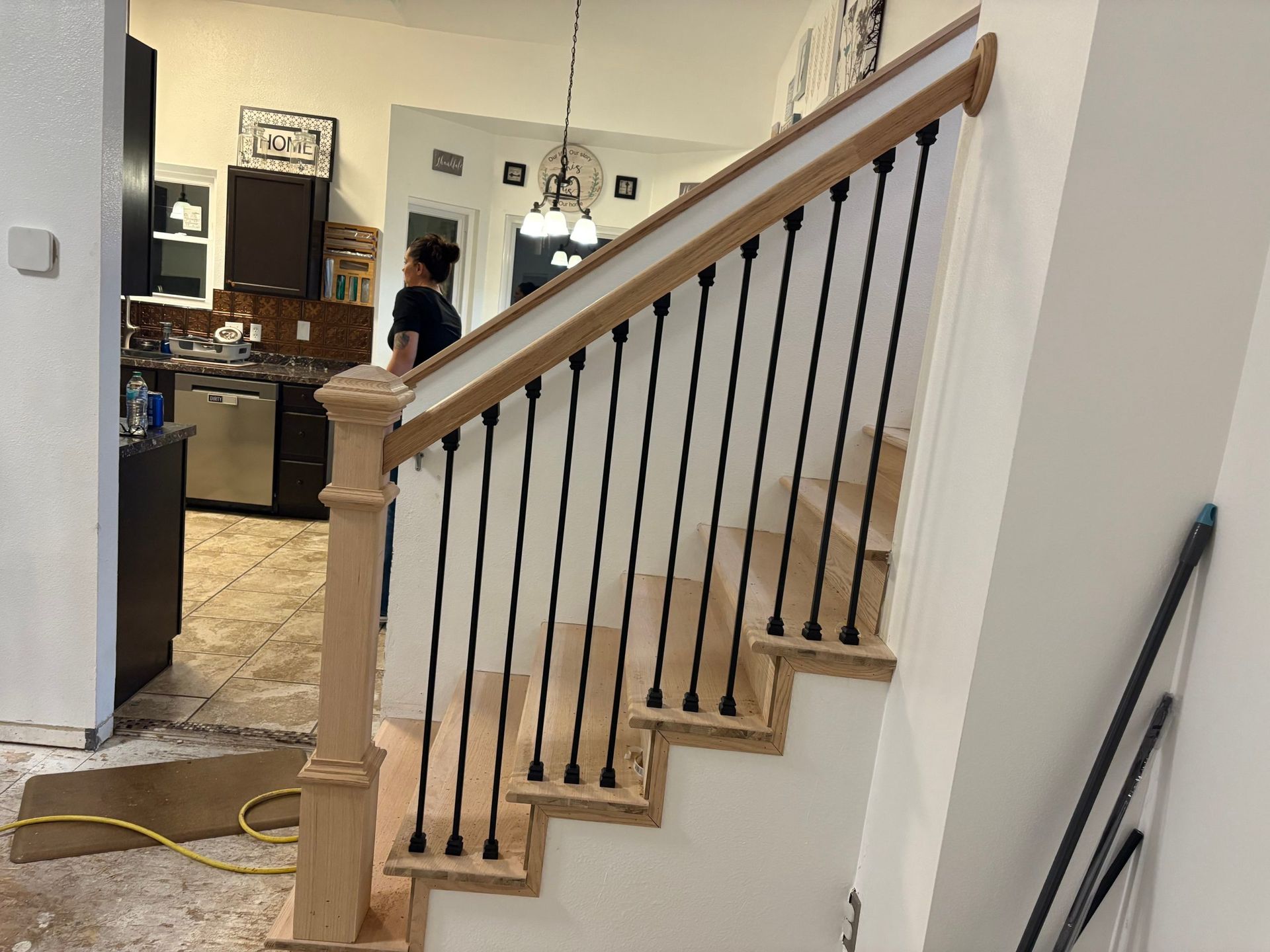 Indoor staircase with beige carpet, dark wooden railings, and a person visible in the background through a doorway.