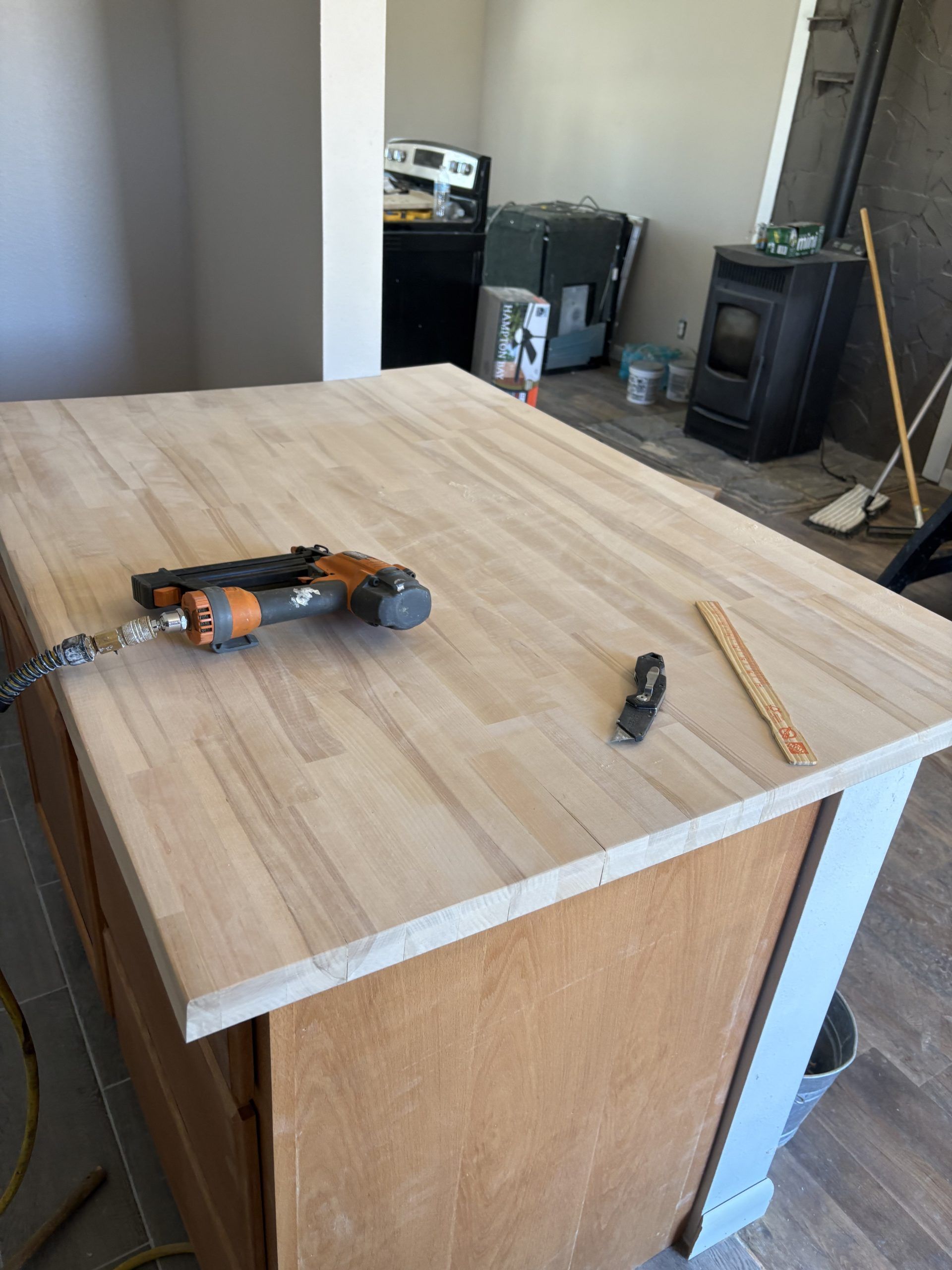 Wooden cabinet top with a power drill and pencil in a room under construction