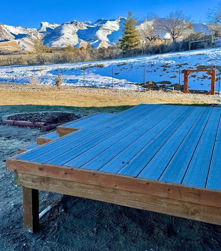 Blue wooden deck overlooking a snowy mountain landscape under a clear sky