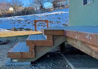 Wooden deck with steps leading up to a house beside a snowy yard