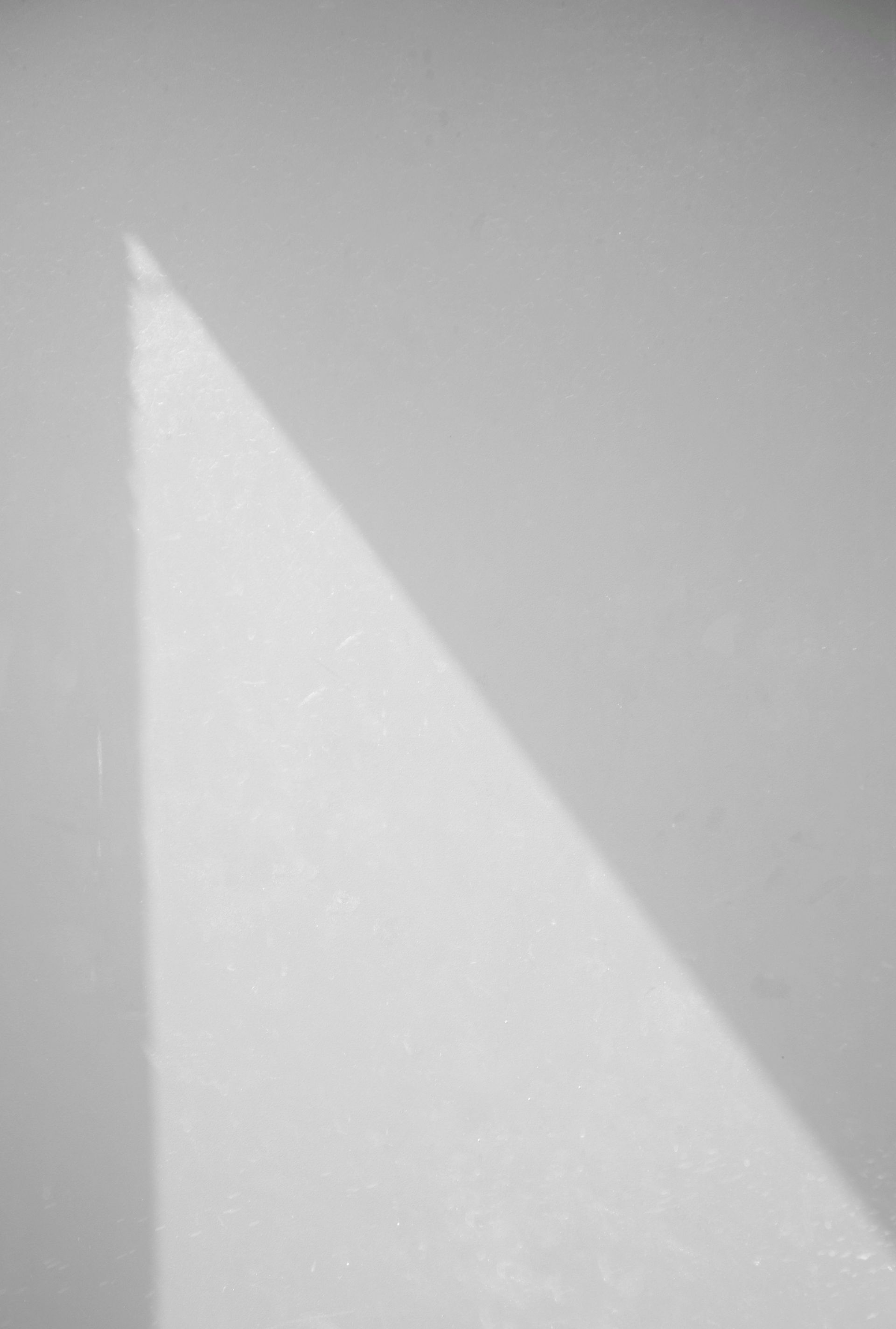 A gray wall with a bright triangular patch of sunlight