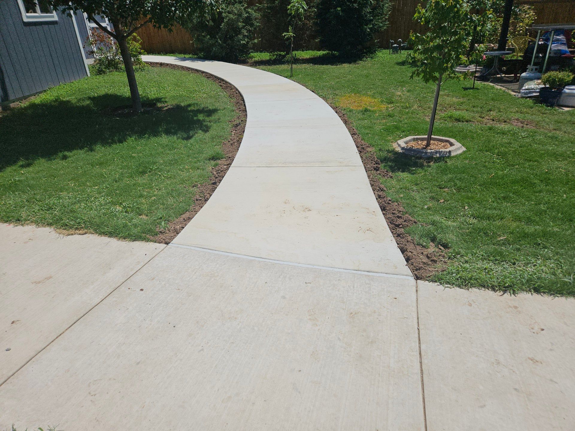 Concrete walkway curving through grassy yard.