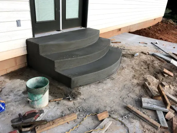 Concrete steps leading up to a doorway on the side of a building; construction debris scattered.