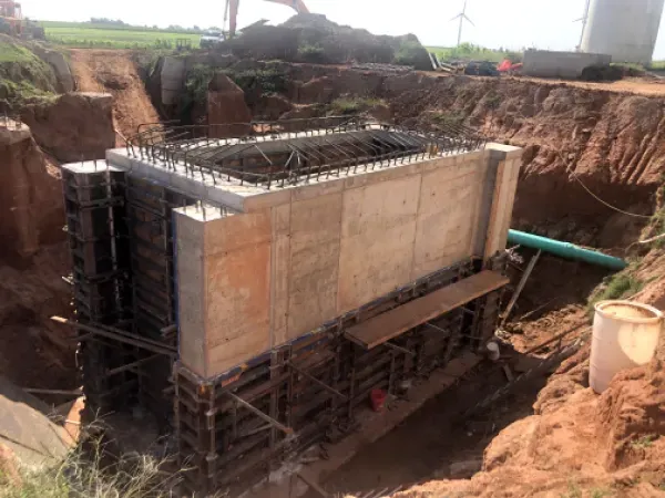 Concrete structure under construction in a deep excavation, surrounded by dirt and construction materials.