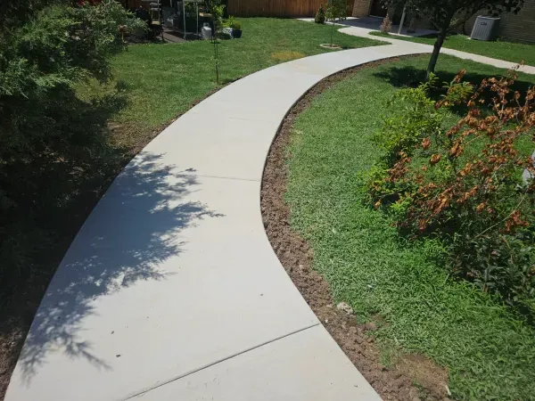 Curving concrete sidewalk through a grassy area.