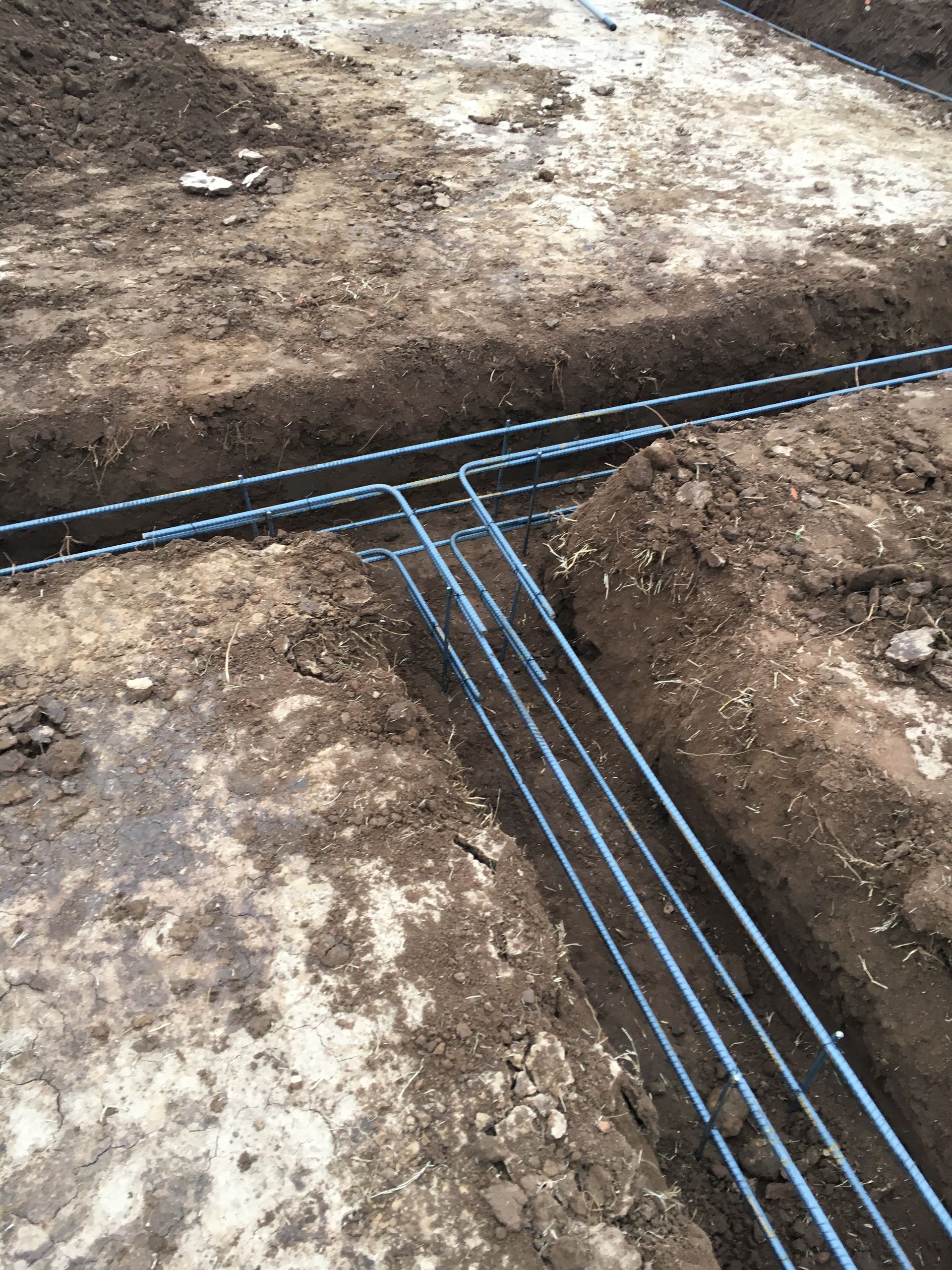 Steel reinforcing bars in trenches, prepared for concrete foundation work.